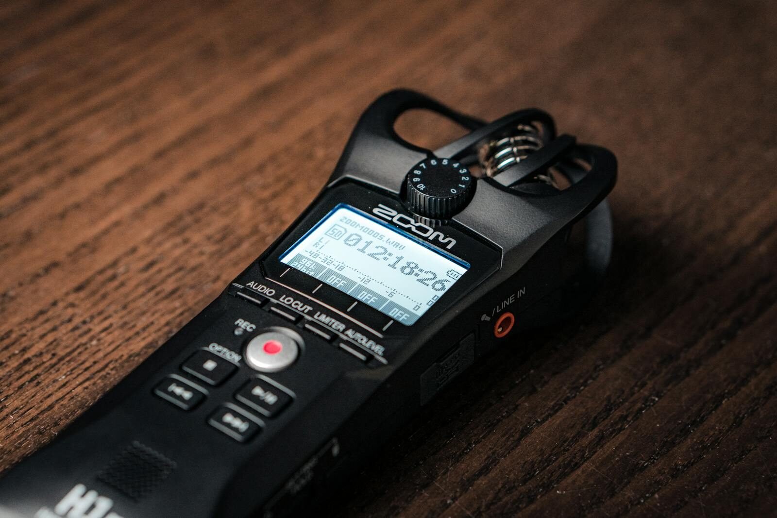Detailed close-up of a digital audio recorder placed on a wooden surface, showcasing modern recording technology.